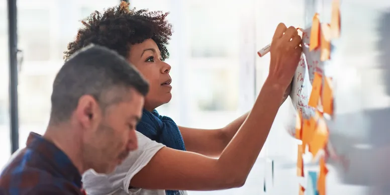 Two people working on a whiteboard